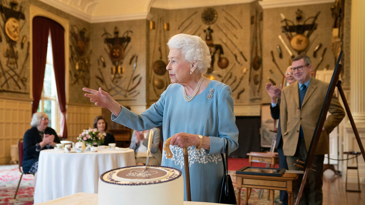 Drottning Elizabeth II skär upp tårta till inbjudna invånare i Sandringham i England.
