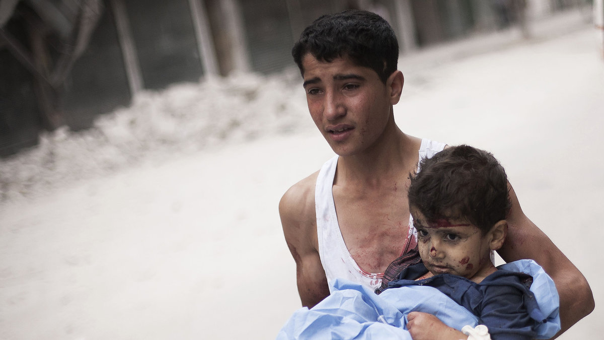 Oktober 2012. En syrisk pojke håller ett barn som skadats av bombningar av syriska armén. 