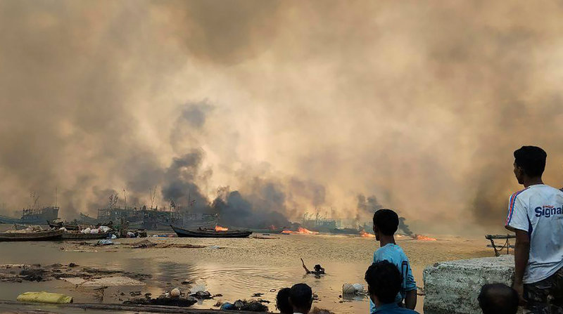 Människor betraktar bränder i byn Kyauk Ni Maw i delstaten Rakhine, efter en bombräd av det myanmariska flygvapnet i januari i år. Bilden har distribuerats av milisgruppen Arakanesiska armén.