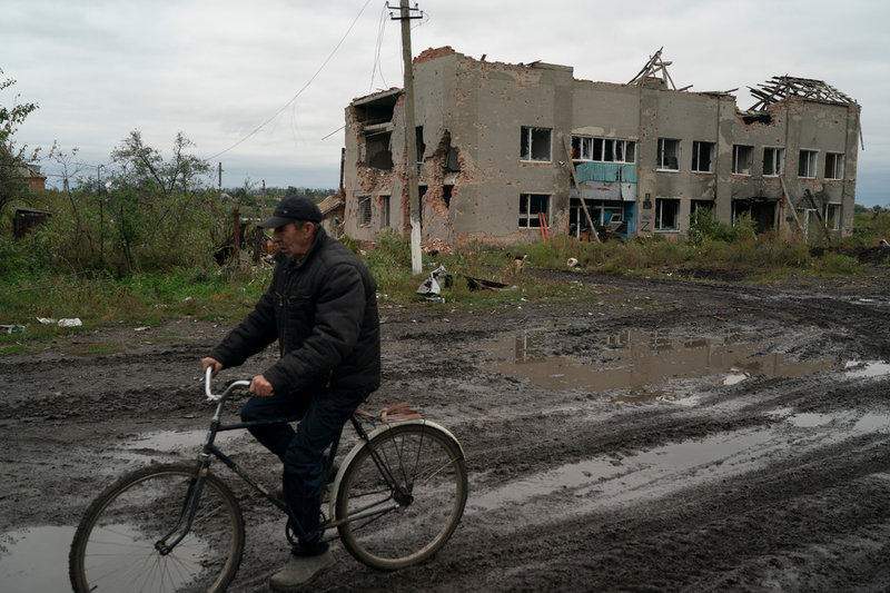 En man cyklar förbi en byggnad som tidigare ockuperades av ryska styrkor. Bild från Charkivregionen den 13 september.