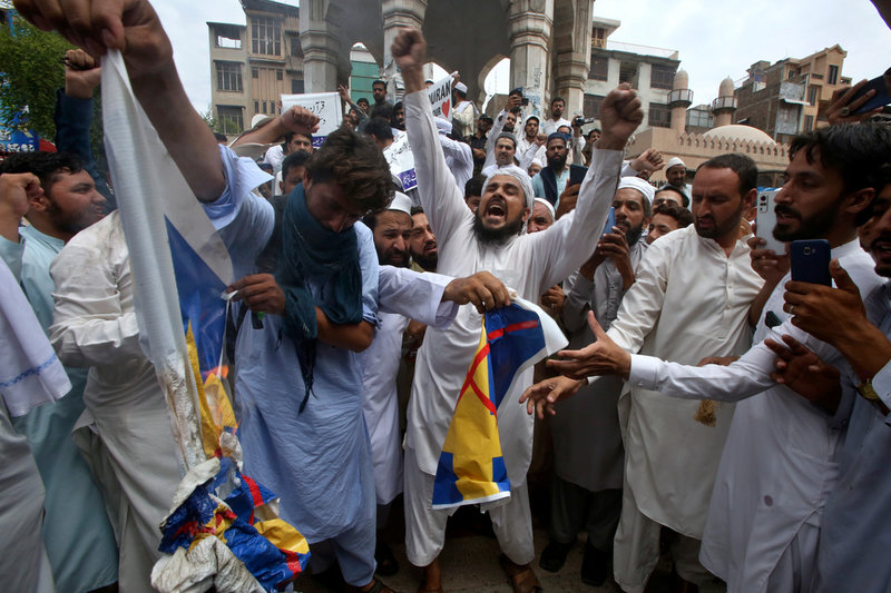 Pakistanska muslimer som är arga för att en koran har eldats upp i Stockholm bränner tygstycken som ser ut som svenska flaggor. Bilden togs i Peshawar i norra Pakistan på fredagen.