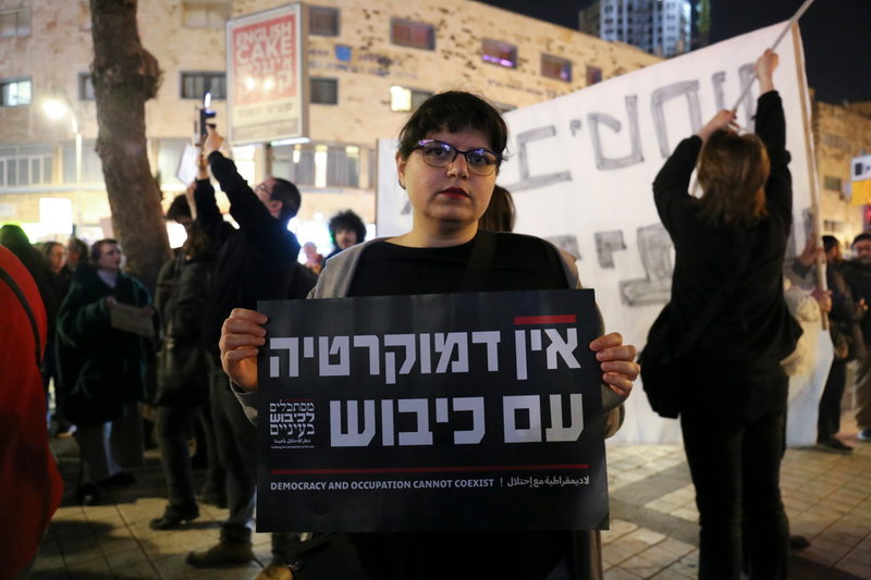 Jerusalembon Noa är orolig för att regeringen kommer att försämra villkoren för palestinier och håller plakatet: 'Demokrati och ockupation kan inte existera samtidigt'.