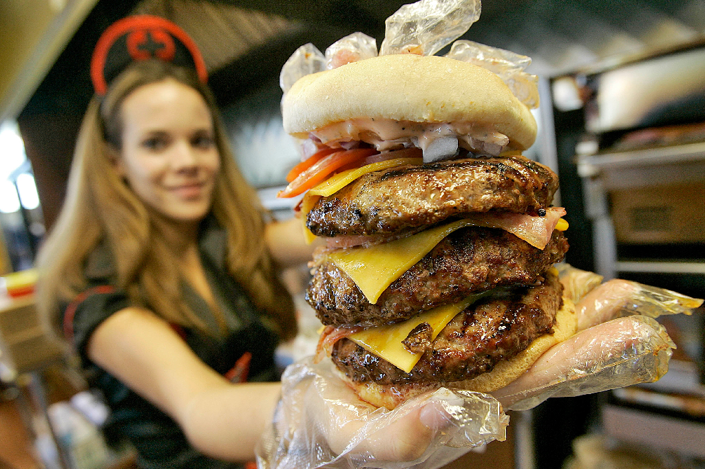En servitris utklädd till sjuksköterska håller upp en triple bypass burger. OBS! Kvinnan på bilden har inget med innehållet i texten att göra. 