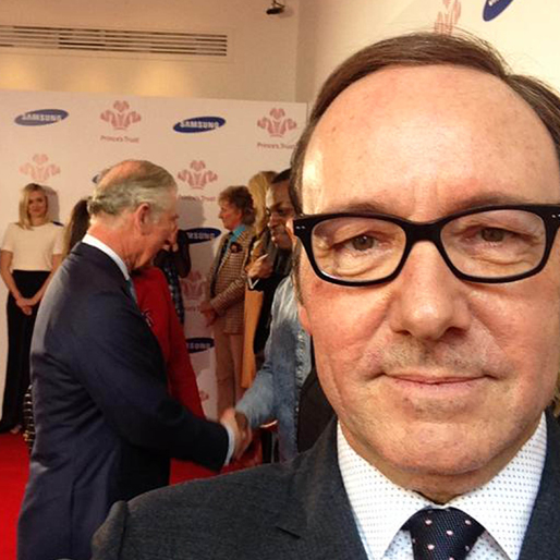 Kevin Spacey tar en selfie med prins Charles i bakgrunden. Kevin Spacey tar en selfie med prins Charles i bakgrunden.