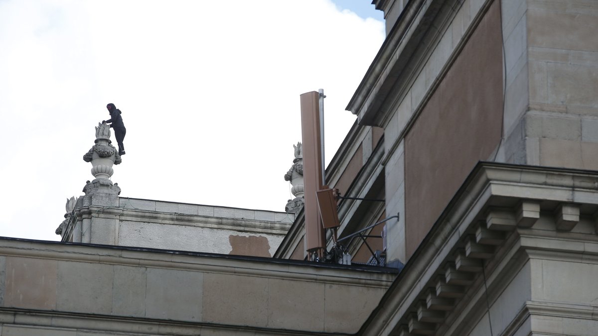 En av två svartklädda, maskerade personer som klättrade upp på Operan i Stockholm i närheten av Kungsträdgården.