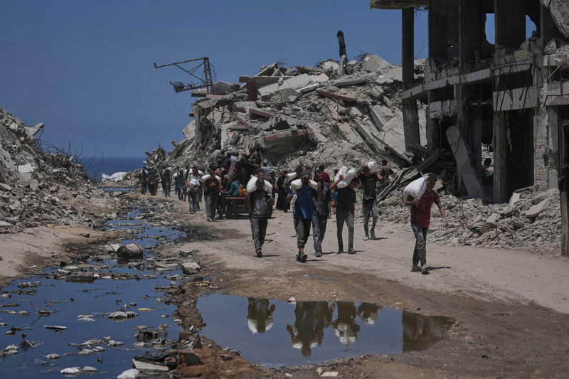 Palestinier bär säckar med mjöl från en humanitär nödkonvoj i Gaza city i norra Gaza på tisdagen.
