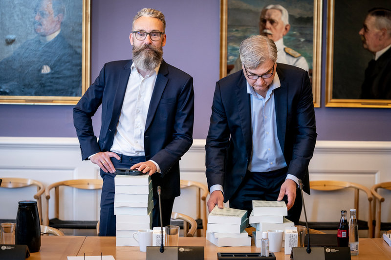 Ole Birk Olesen, Liberal Alliance, och Peter Seier Christensen, Nye Borgerlige, med minkkommissionens nio band stora rapport.