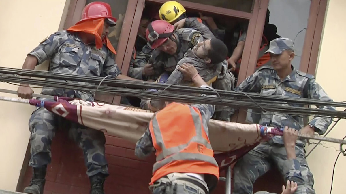På bilden (som är från en video) syns räddningsarbetare rädda en överlevare från en byggnad skadad i jordbävningen.
