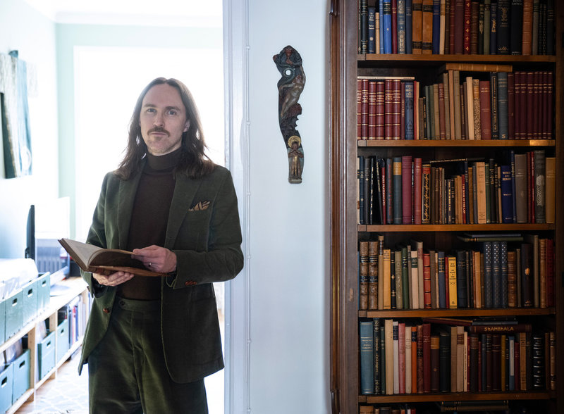 Per Faxneld hemma i lägenheten i Stockholm, där ett stort bibliotek samsas med masker från olika världsdelar. 