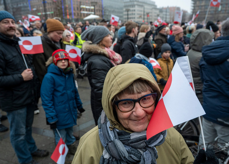 Pensionen Merete går i demonstrationståget med den grönländska flaggan i handen.