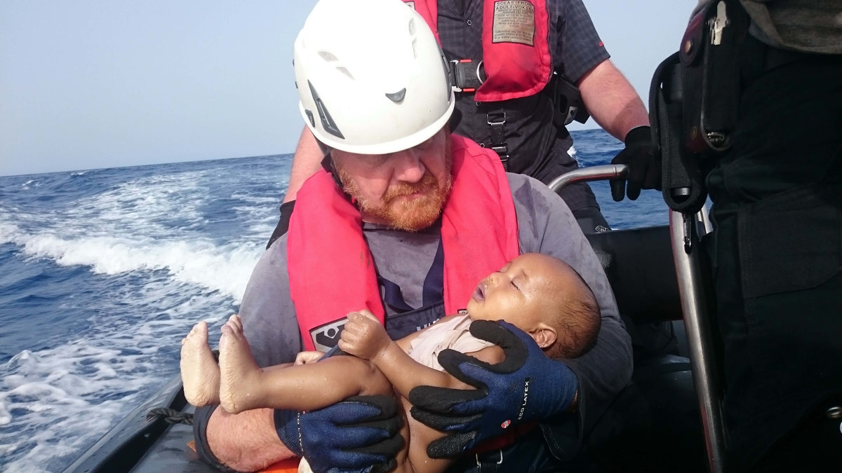 En besättningsmedlem ur en humanitär organisation håller ett drunknat flyktingbarn i famnen.