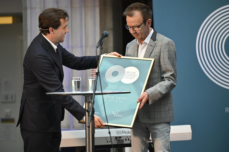 Björn Skifs tar emot regeringens hederspris för mångåriga insatser för svensk musikexport från Sveriges bistånds- och utrikeshandelsminister Benjamin Dousa (M).