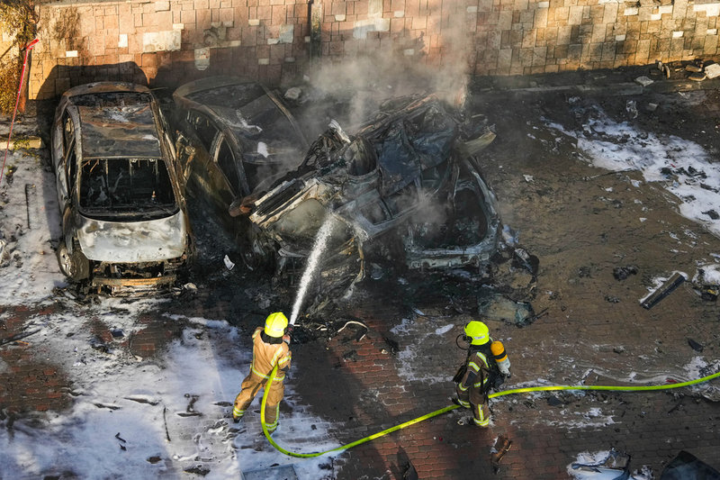 Räddningstjänsten släcker en brand efter det att en raket från Gaza slagit ned på en parkeringsplats i Ashkelon i Israel.