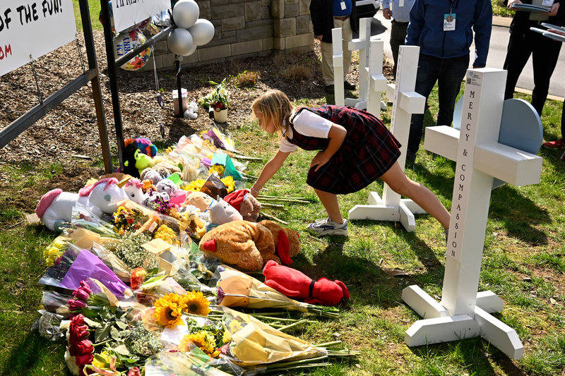 En ung flicka lägger ner blommor vid en minnesplats för barn som sköts ihjäl vid Covenant School i Nashville i mars i år.