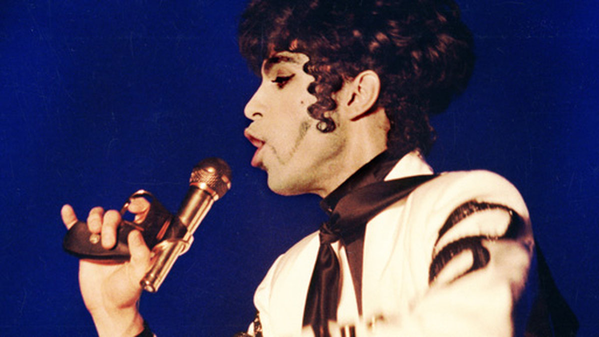 Här sjunger Prince i en mix av mikrofon och pistol. 