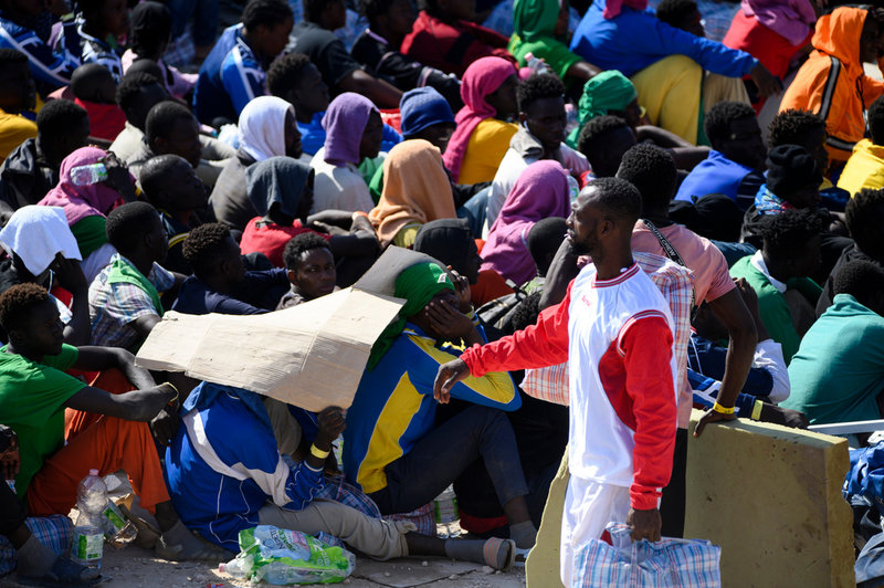 Migranter utanför Röda Korsets mottagningscenter på den italienska ön Lampedusa, en så kallad 'hot spot' där ingen är tänkt att stanna mer än tre dygn. Bilden togs i torsdags, dagen efter att över 6 800 migranter anlänt till ön.