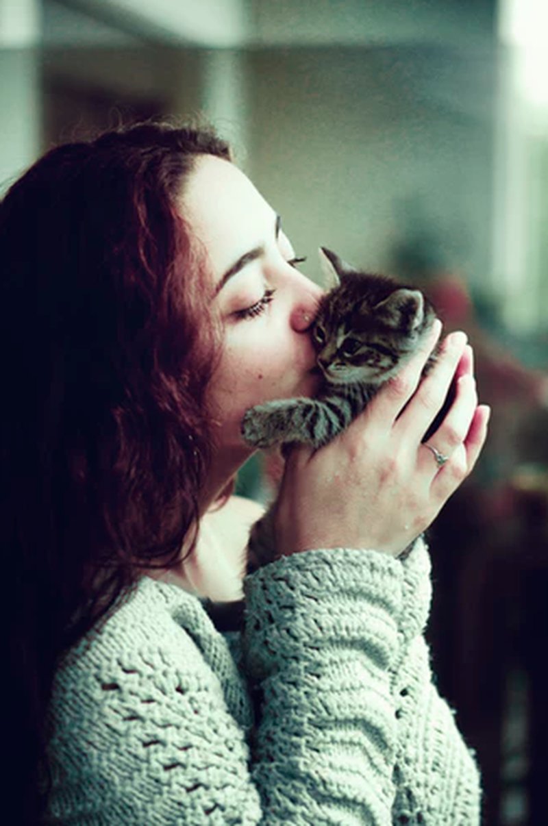 En kvinna pussar en katt