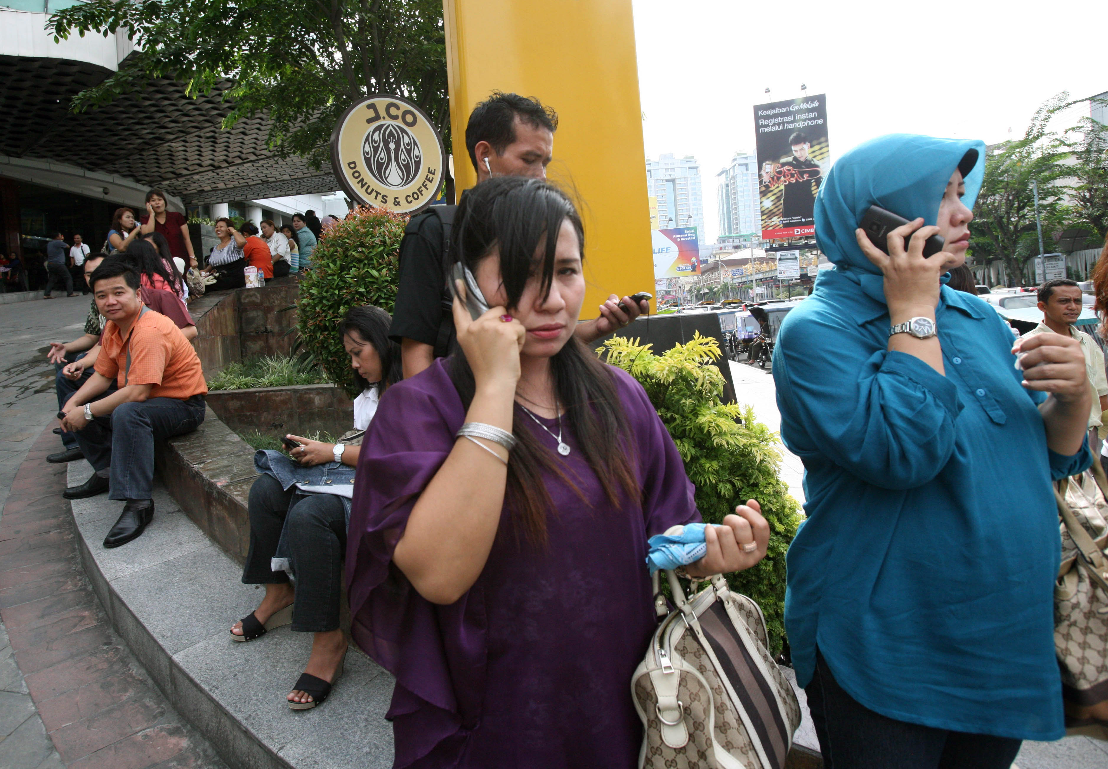 Indonesiska kvinnor ringer anhöriga efter att ha evakuerats från en galleria i Medan.