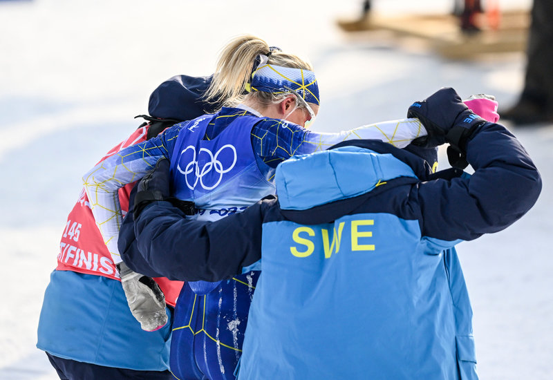 En talade bild för Frida Karlssons OS. Skidstjärnan får hjälp av svenska ledare att ta sig ut från målområdet efter kollapsen på 10 kilometer.