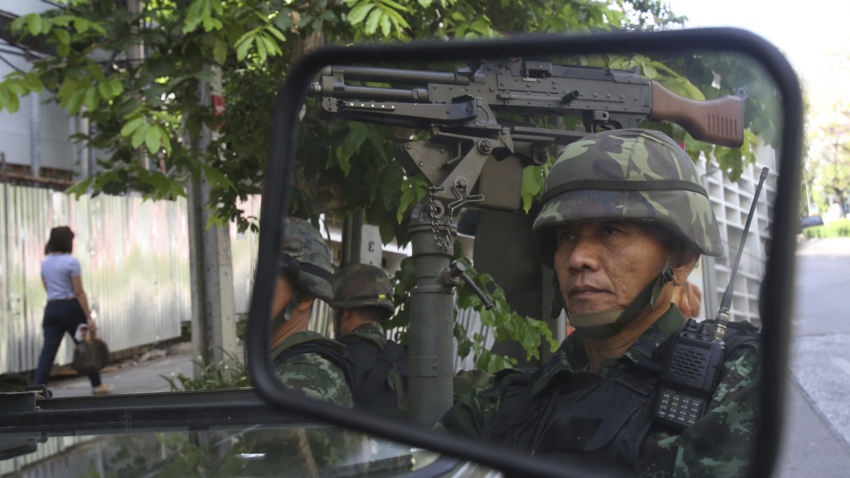 En thailändsk soldat reflekteras i en spegel när han står vakt utanför polisens högkvarter.  