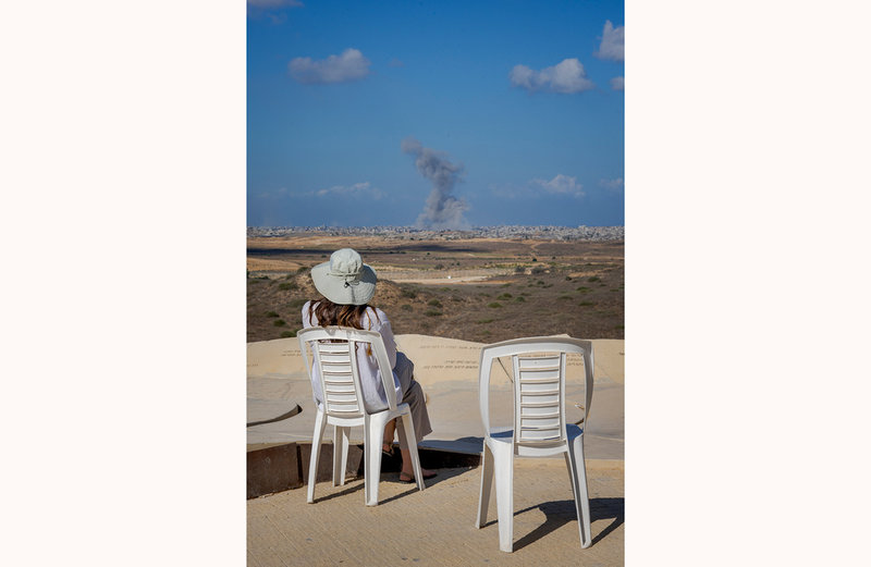 Årets bild är tagen av Alexander Mahmoud. Den 7 oktober 2025 sitter en kvinna på en utsiktsplats i Sderot i södra Israel och tittar på rökpelare som stiger upp mot himlen i norra Gaza. Pressbild. 