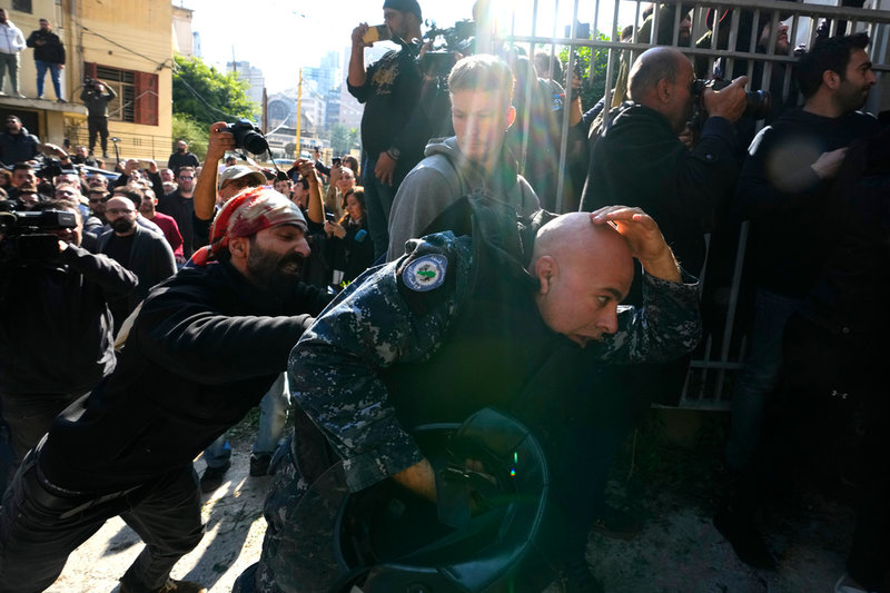 Regeringskritiska demonstranter slår en polis utanför justitiedepartementet i Beirut den 26 januari.
