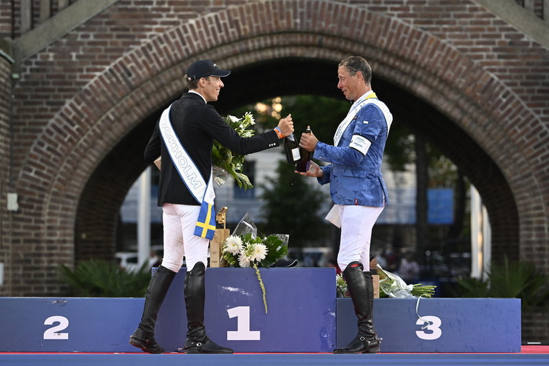 Tvåan Henrik von Eckermann skålar med vinnaren, tysken Christian Ahlmann efter GP-hoppningen i lördags. Den svenske ryttarstjärnan hade stora framgångar på Stockholms stadion.
