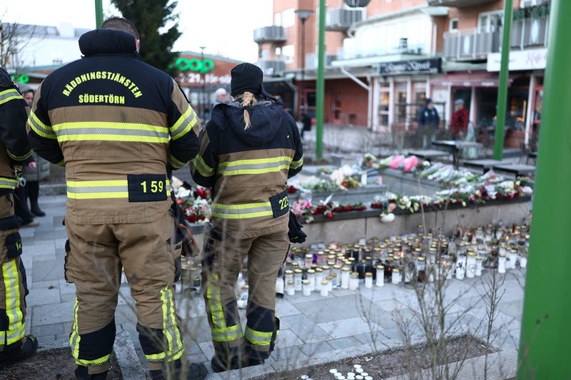 Personal ur räddningstjänsten lämnar en bukett vid minnesplatsen.