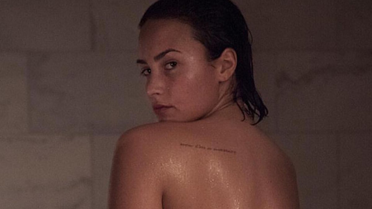 Demi Lovato poserar vid badkarskanten. 
