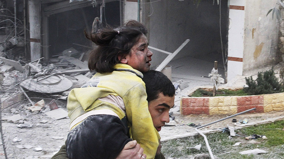 En syrisk ung man bär iväg sin skadade lillasyster efter en flygattack från syriska regimen. Februari 2013.
