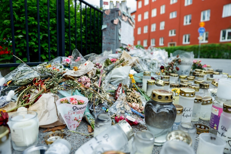 Blommor och ljus vid en minnesplats i närheten av frisersalongen där tre personer sköts ihjäl i Uppsala. Bild från maj 2025. 
