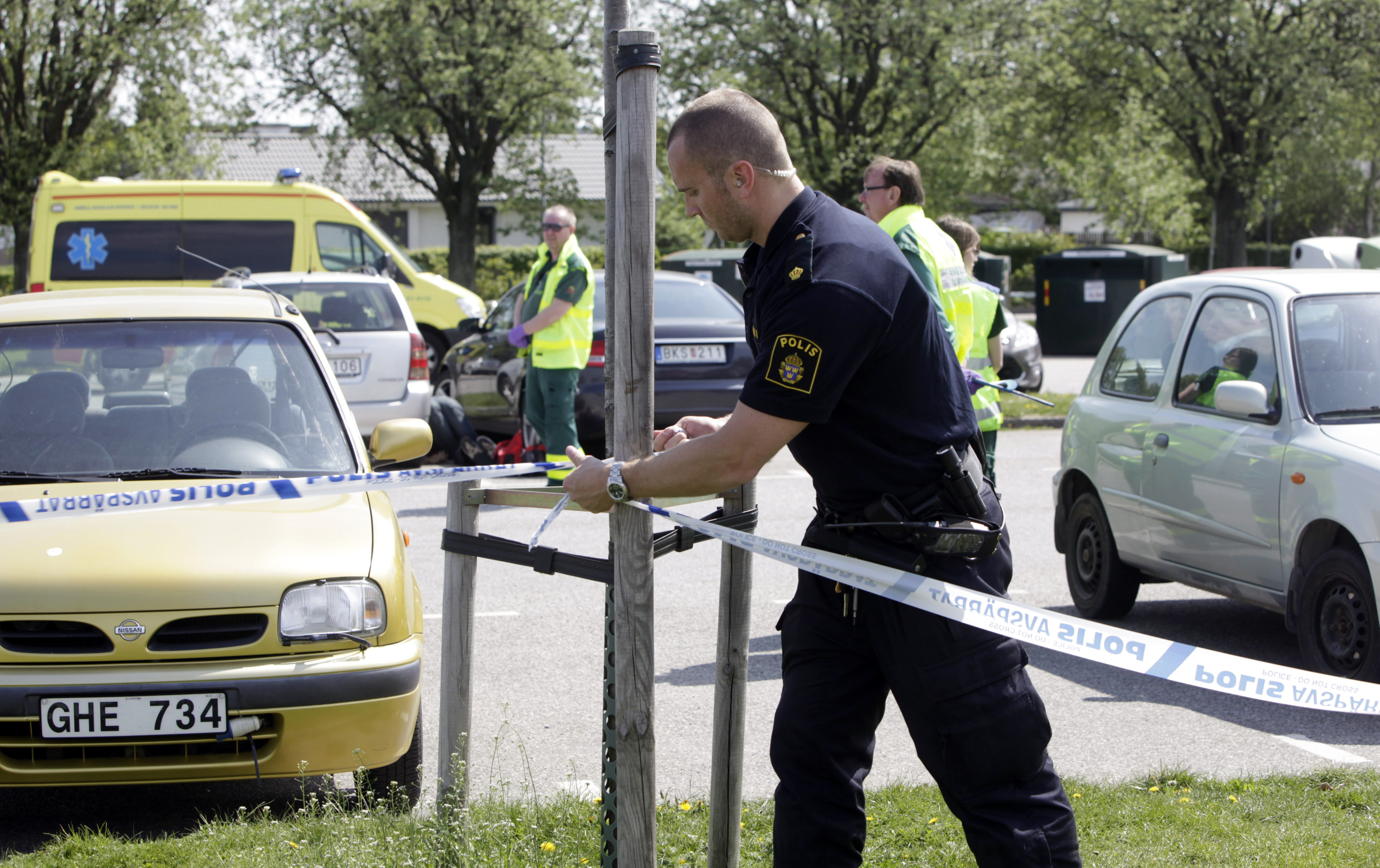 Här spärrar polisen av ett område vid Sibbarp. I bakgrunden skymtar den skjutne mannen mellan bilarna.