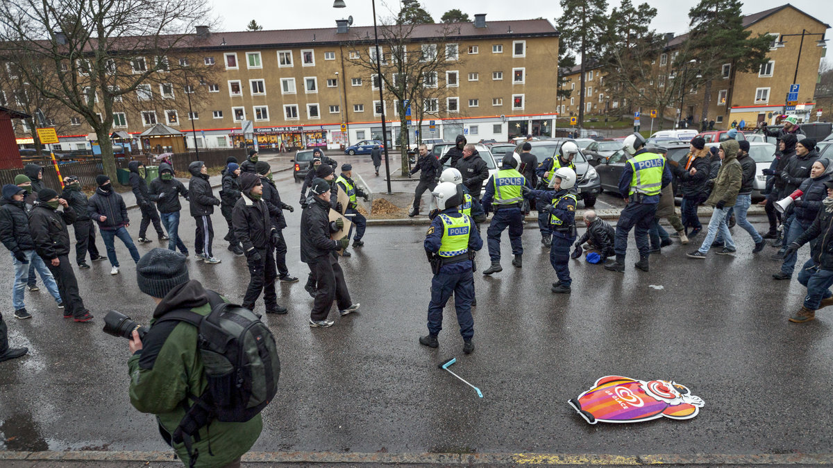 Ögonblicksbild från Kärrtorp i december 2013. Till vänster: De svartklädda SMR-aktivisterna.