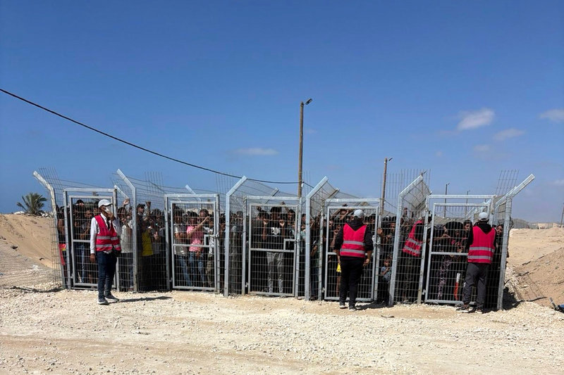 En bild tillhandahållen av en anonym amerikansk GHF-anställd visar palestinier som väntar bakom galler inför en matutdelning i Gazaremsan i maj.