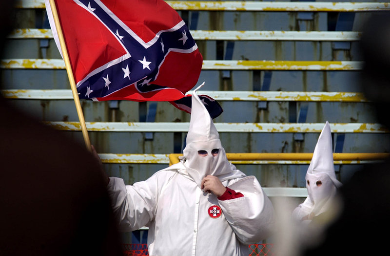En Ku Klux Klan-medlem med en Sydstatsflagga år 2001. En Ku Klux Klan-medlem med en Sydstatsflagga år 2001.