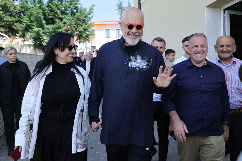 Albaniens sittande premiärminister Edi Rama (mitten) lämnar en vallokal tillsammans med sin fru.