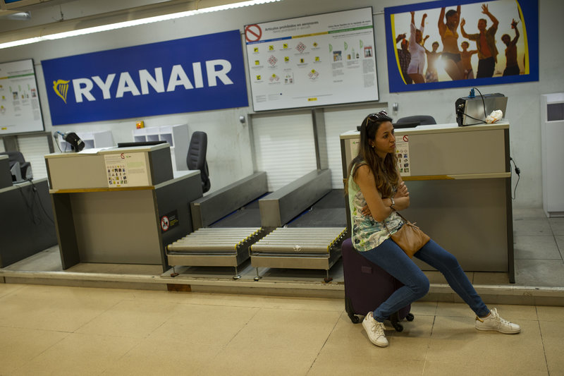 En kvinna som sitter på sin resväska på en flygplats. En kvinna som sitter på sin resväska på en flygplats.