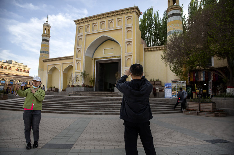 Besökare poserar utanför Id Kah-moskén i Kashgar, under en statligt organiserad tur för utländska journalister 2021.