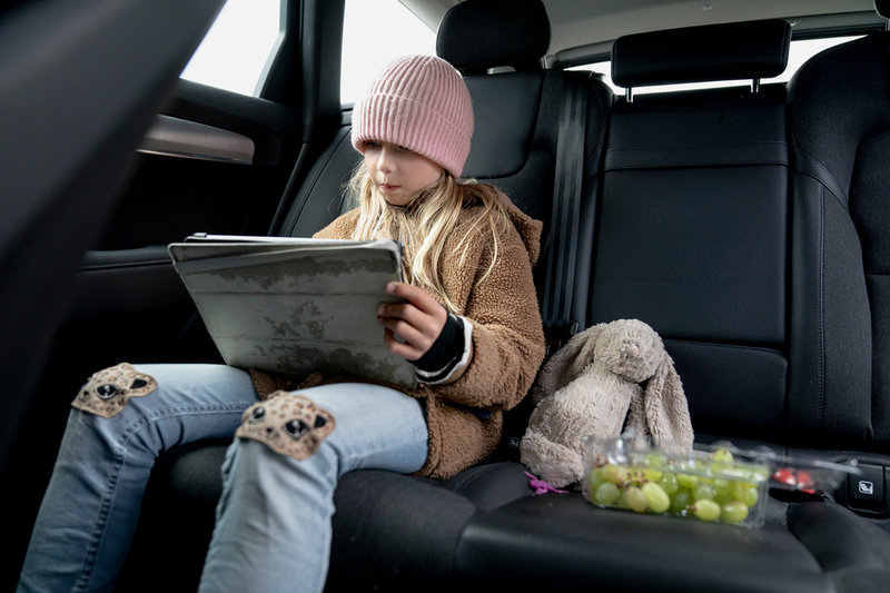 Sally Hassel, 8, värmer sig i bilen medan mamma Emilie Hassel väntar utanför passexpeditionen.