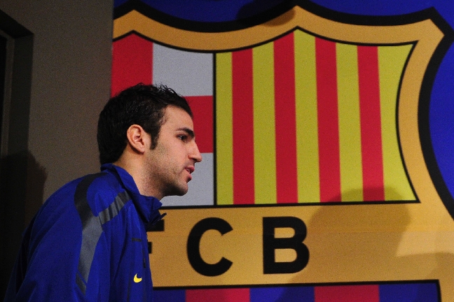 Cesc Fabregas går förbi en stor plansch föreställandes Barcelonas klubbemblem, när han fortfarande tillhörde Arsenal.