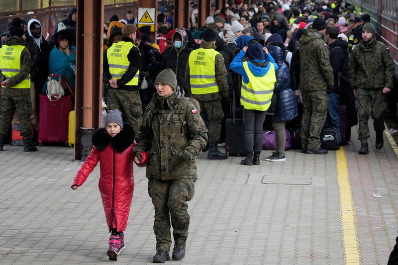 En flicka som flytt Ukraina tas emot av militär på tågstationen i polska staden Przemysl. Arkivbild.