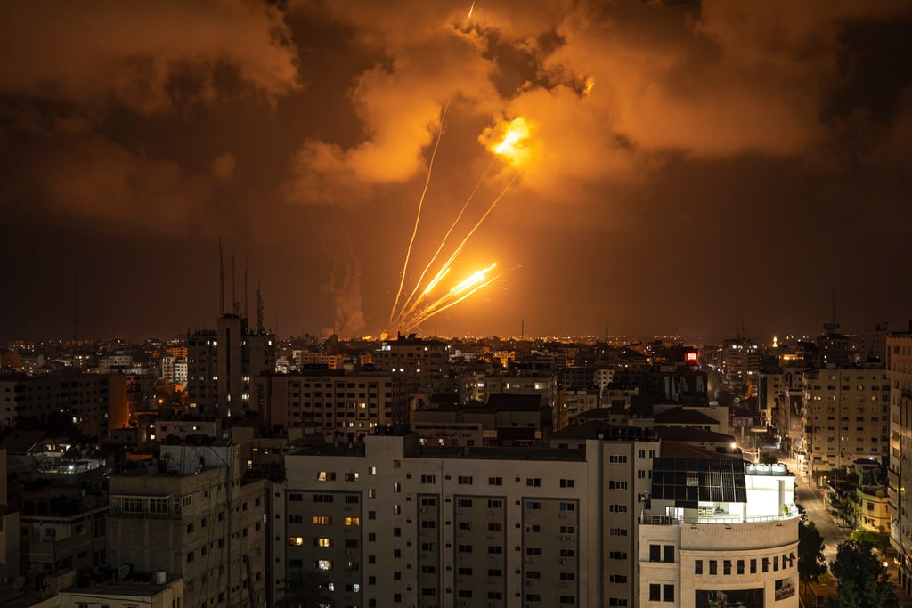 Raketer som avfyras mot Israel lyser upp kvällshimlen i staden Gaza.