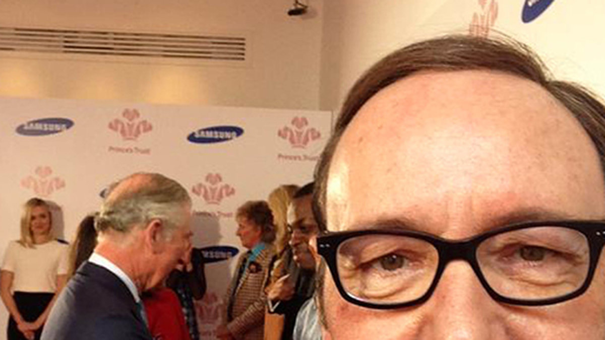 Kevin Spacey tar en selfie med prins Charles i bakgrunden. 