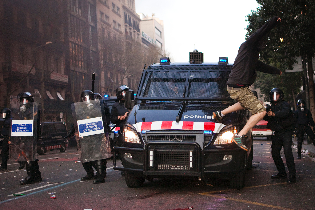 En demonstrant visar sitt missnöje mot polisen genom att hoppa på polisbilen.