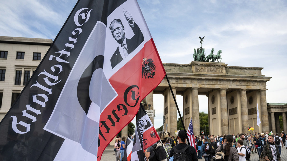 En demonstrant håller det tidigare tyska rikets svart-vit-röda flagga vid en demonstration framför Brandenburger Tor i Berlin, i augusti 2020. Flaggan används av Reichsbürger-rörelsen och just denna pryds också av bland andra Donald Trump. Arkivbild.