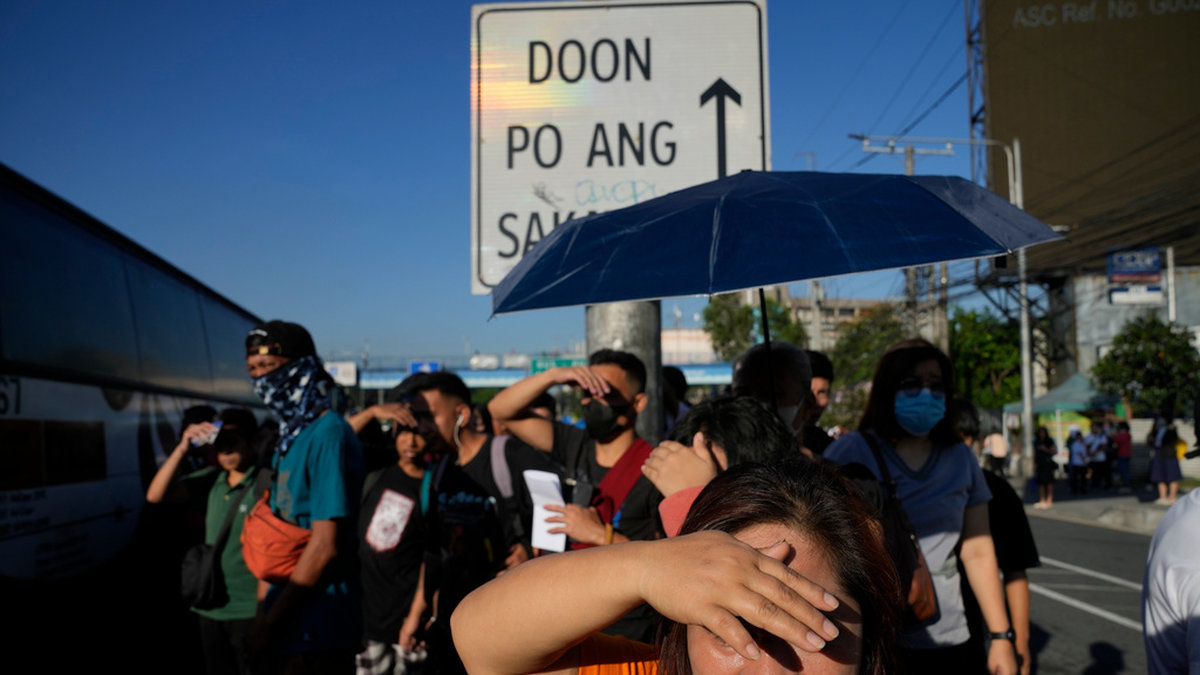 Pendlare försöker undvika solen under värmeböljan i filippinska Quezon City tidigare i april.