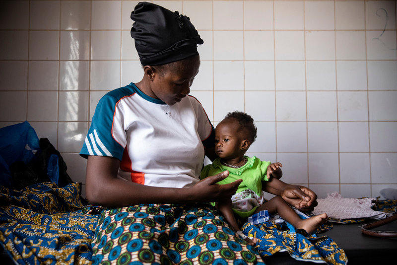 Martine Roamba och hennes tio månader gamla dotter Leïla väntar på att få vård på barnavdelningen på Boulmiougousjukhuset i Ouagadougou, tidigare i år. Flickan får inte i sig tillräckligt med näring eftersom Martine Roamba själv inte fått tillräckligt med mat sedan hon tvingades på flykt förra året och därmed inte heller har så mycket bröstmjölk.