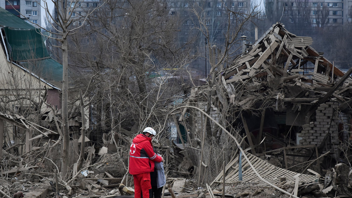 En räddningsarbetare tröstar en kvinna efter ett ryskt flyganfall som förstörde en länga bostadshus i Zaporizjzja-regionen i slutet av mars i år. Arkivbild.