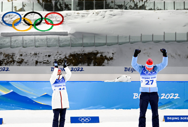 Guldmedaljören Johannes Thingnes Bø (tv) applåderar sin bror och bronsmedaljören Tarjei Bø efter herrarnas sprint.