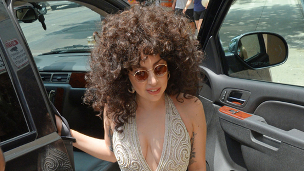 Lady Gaga i lockigt hår och beige klänning. 